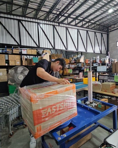 พนักงาน FastShip กำลังห่อพลาสติกยืดพัสดุให้พร้อมสำหรับ Shipment