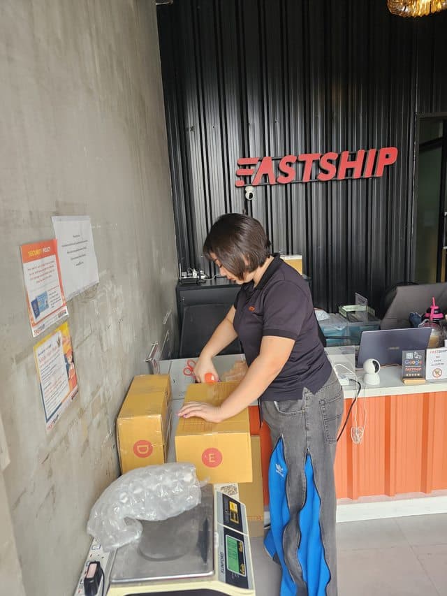 พนักงาน FastShip กำลังติดป้ายกล่องพัสดุก่อนจัดส่ง