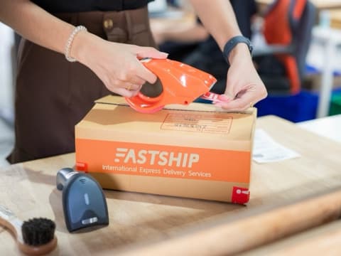 พนักงานกำลังแพ็กและติดเทปกล่องพัสดุ FastShip